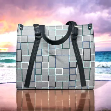 Here's an alt tag for the image: Gray geometric tote bag on beach.