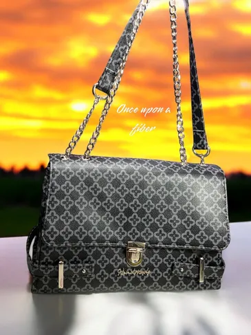 Black patterned shoulder bag with gold chain.