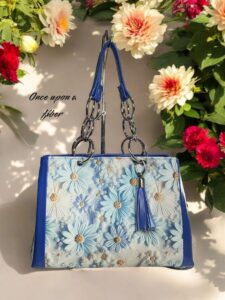 Blue floral handbag with chain straps.