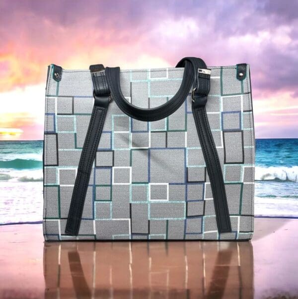 Grey geometric tote bag on beach.