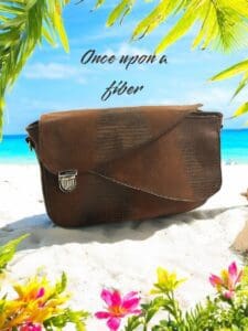 Brown leather crossbody bag on beach.