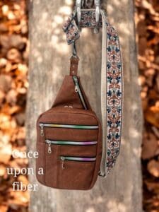 Brown crossbody bag with patterned strap.