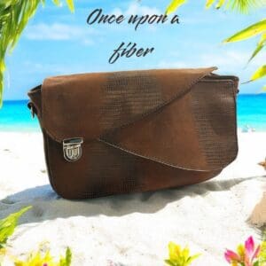 Brown leather crossbody bag on beach.