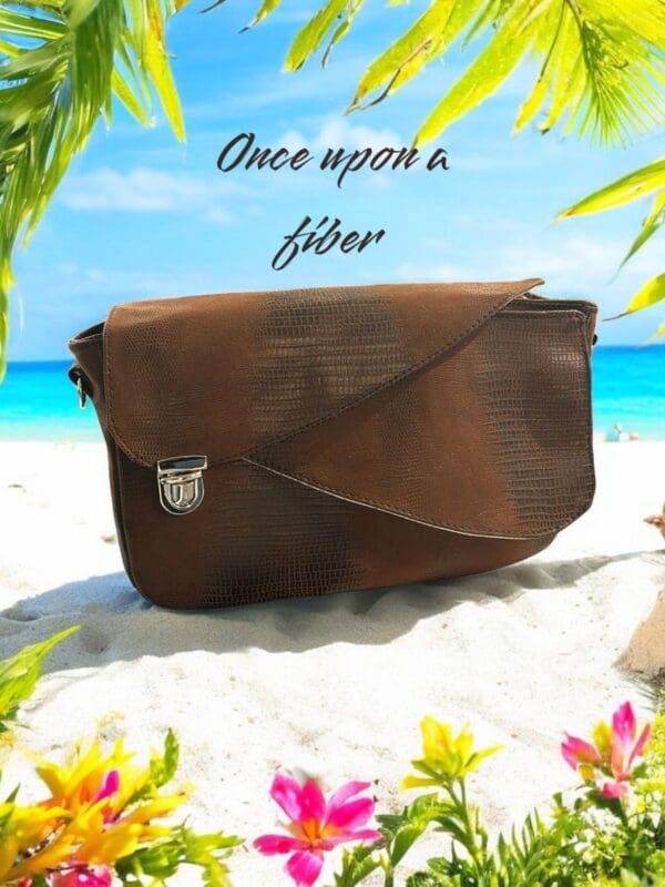 Brown leather crossbody bag on beach.