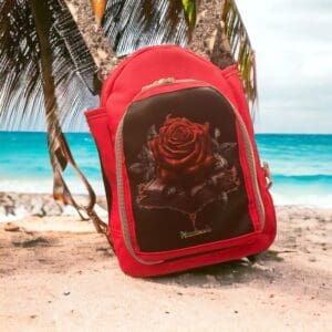 Red backpack with rose design on beach.